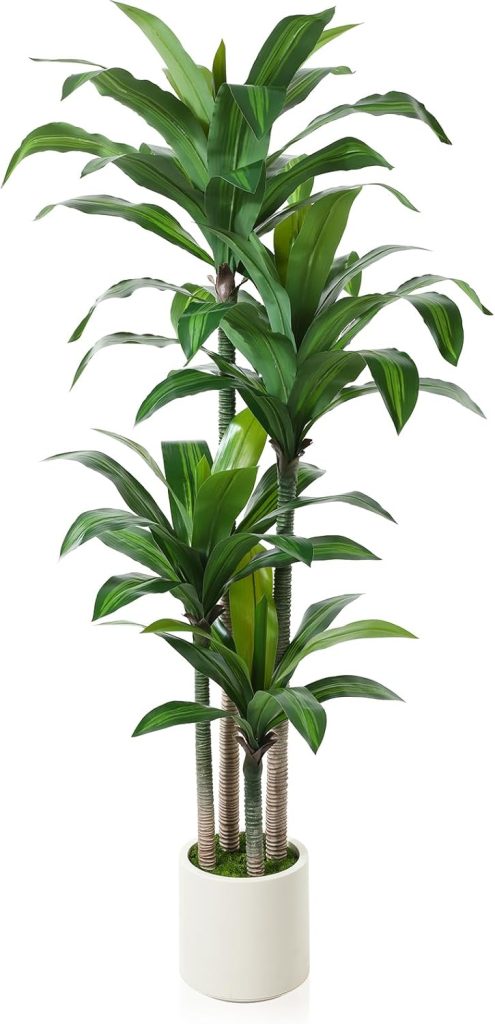 Tall artificial dracaena tree in a white planter styled beside a modern home office desk, ergonomic chair, bookcase, and triptych wall art.