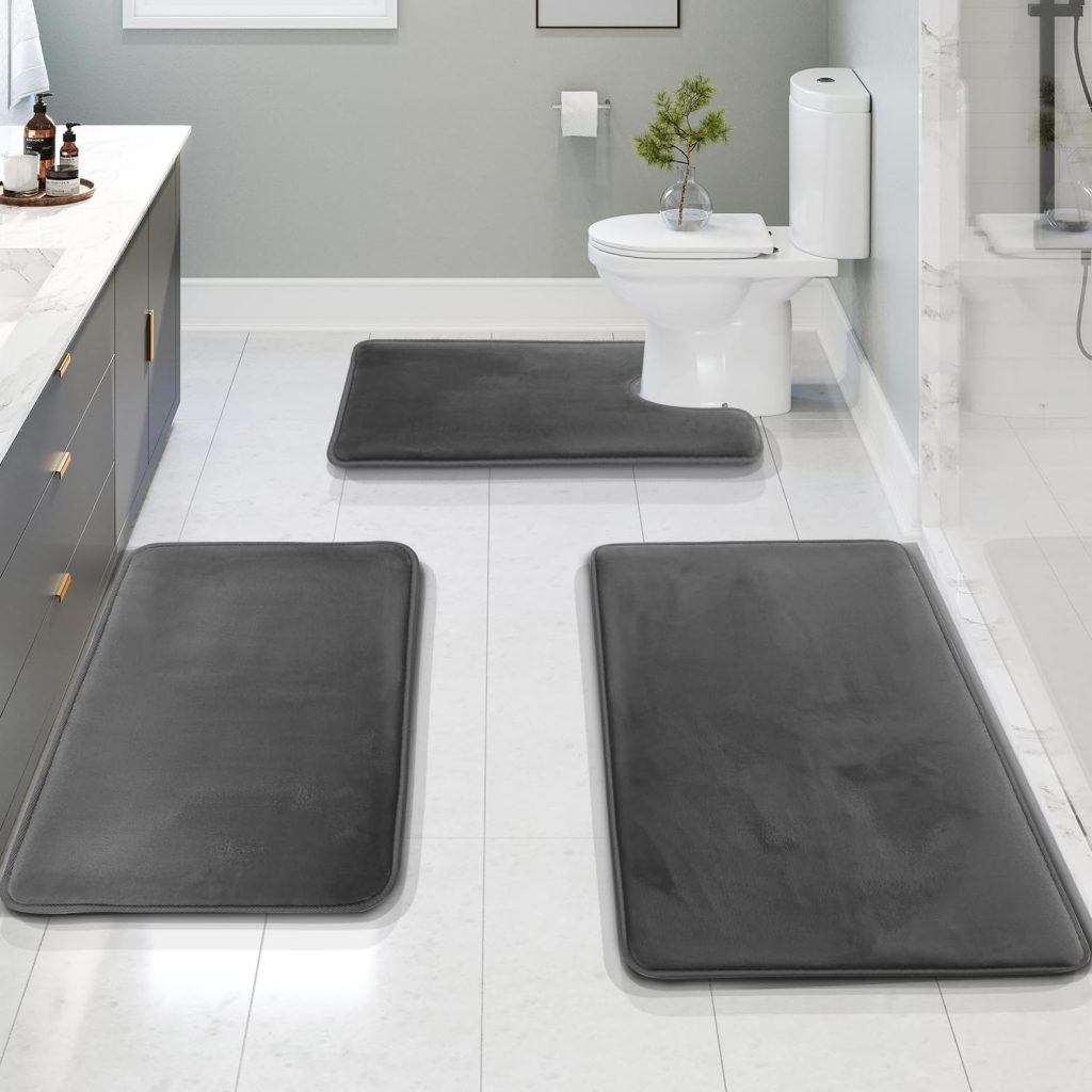 Grey Clara Clark bathroom rug set styled in a modern bathroom with wood vanity, round wall mirror, floating shelves, white shower curtain, towels, and spa-inspired decor.