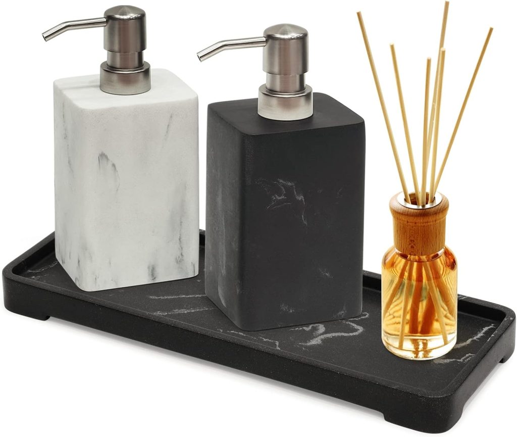 Black and white marble style soap dispenser set on a modern bathroom vanity with wood cabinets, round mirror, soft lighting, and neutral decor.