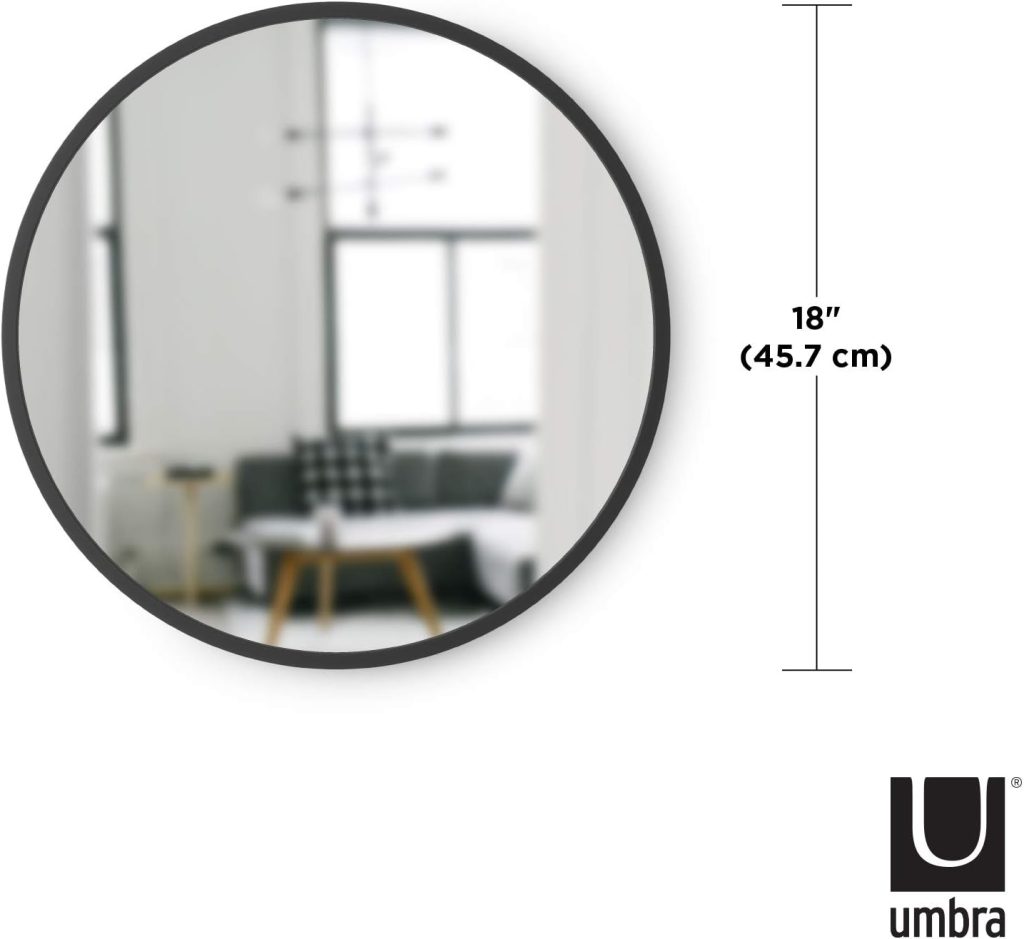 Black Umbra Hub round wall mirror styled above a bathroom vanity with modern bathroom decor, wood accents, floating shelves, and soft vanity lighting.